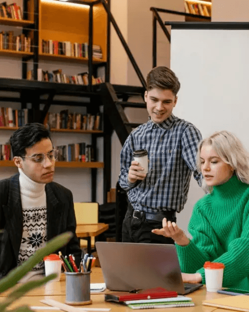 People collaborating in a library setting with bookshelves