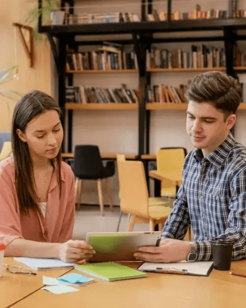Two people collaborating at a desk in library